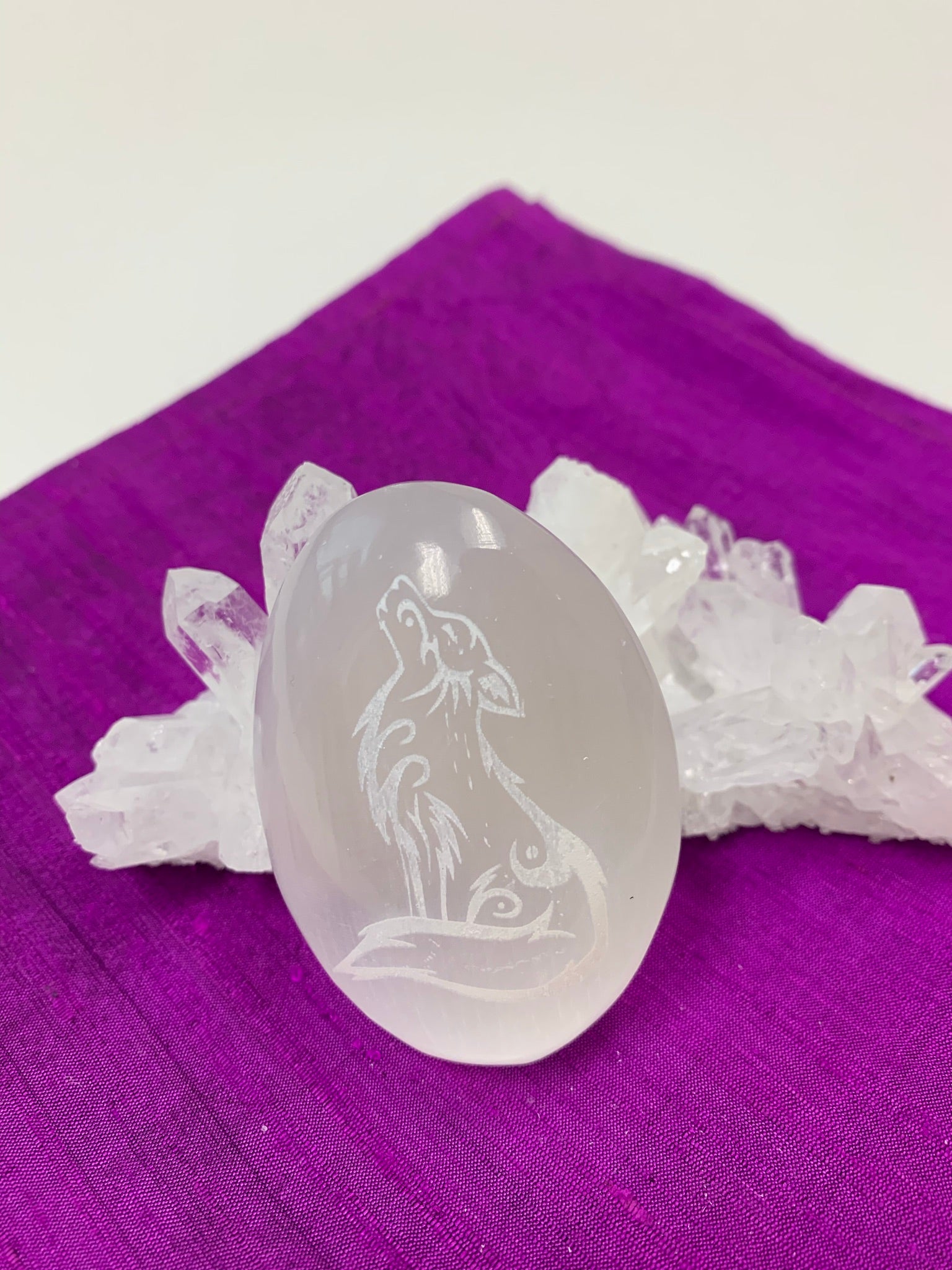 Wolf etched on smooth, polished white selenite palm stone. The selenite ranges from translucent to milky white in color. Wolf is intuitive, the teacher bringing knowledge back to the pack, is loyal and family oriented but also has an individualistic instinct. The weight of each stone varies, but the average is 4.2 oz and the size is approximately 3"x2.5".  These selenite stones are handcrafted and etched with lasers and by hand. This selenite is sourced ethically and workers are paid living wages. 