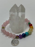 Load image into Gallery viewer, Close-up view of the quartz gemstone power bracelet, accented with 7 gemstone beads to match the chakras. It has 3 accent beads - silver colored or rainbow-ish colored (these are not gemstones). The bracelet also includes a silver-colored lotus charm (not sterling silver). The gemstones are genuine, but the color has been enhanced on this line of power bracelets. There are other bracelets available in the store with the natural color only.
