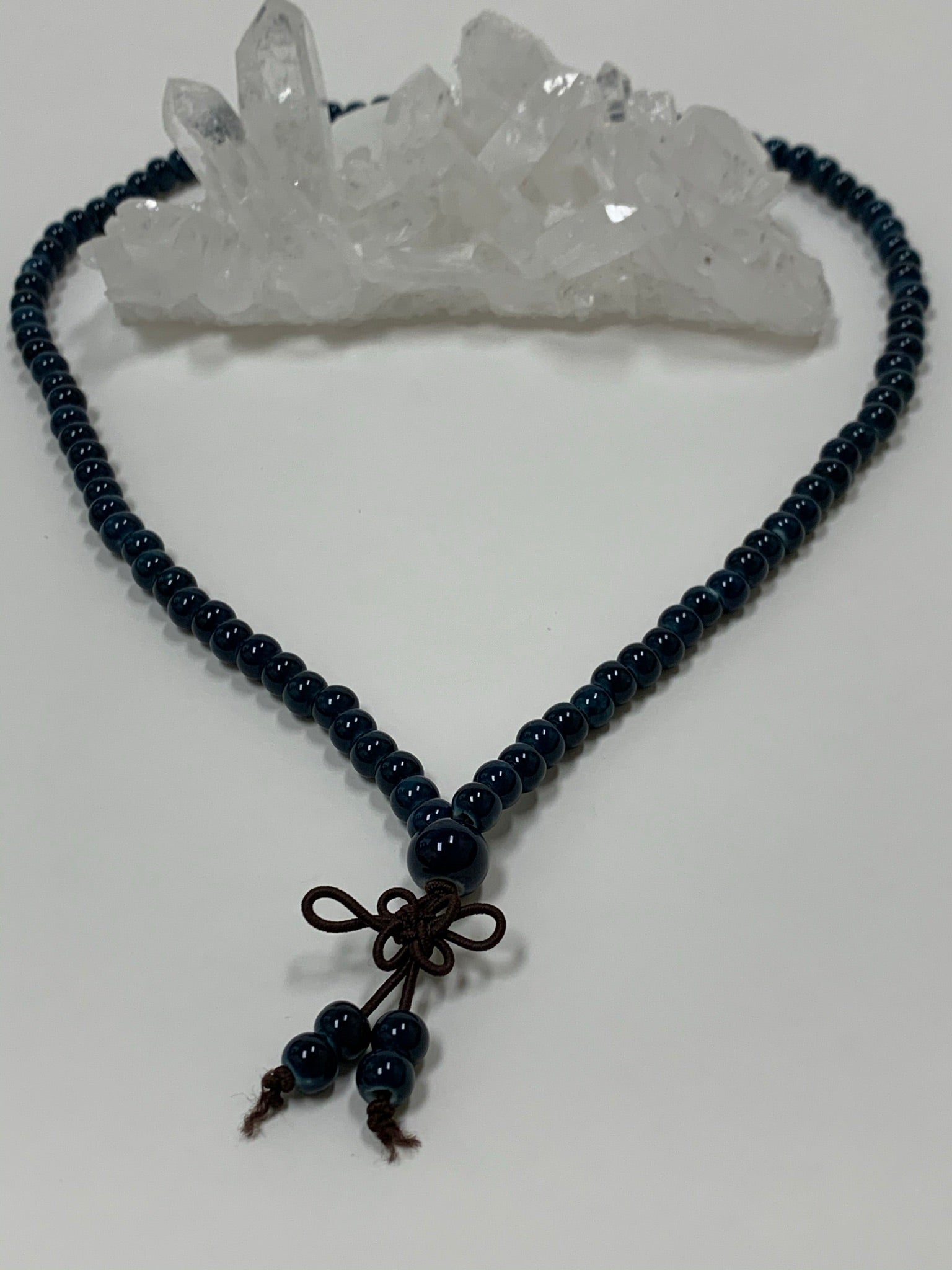 Second close-up view. Prayer beads/mala necklace consists of 108 small, blue ceramic beads. Used to count 108 repetitions of a mantra, so the user can pay attention to the sounds, vibrations and meaning of the mantra being chanted.