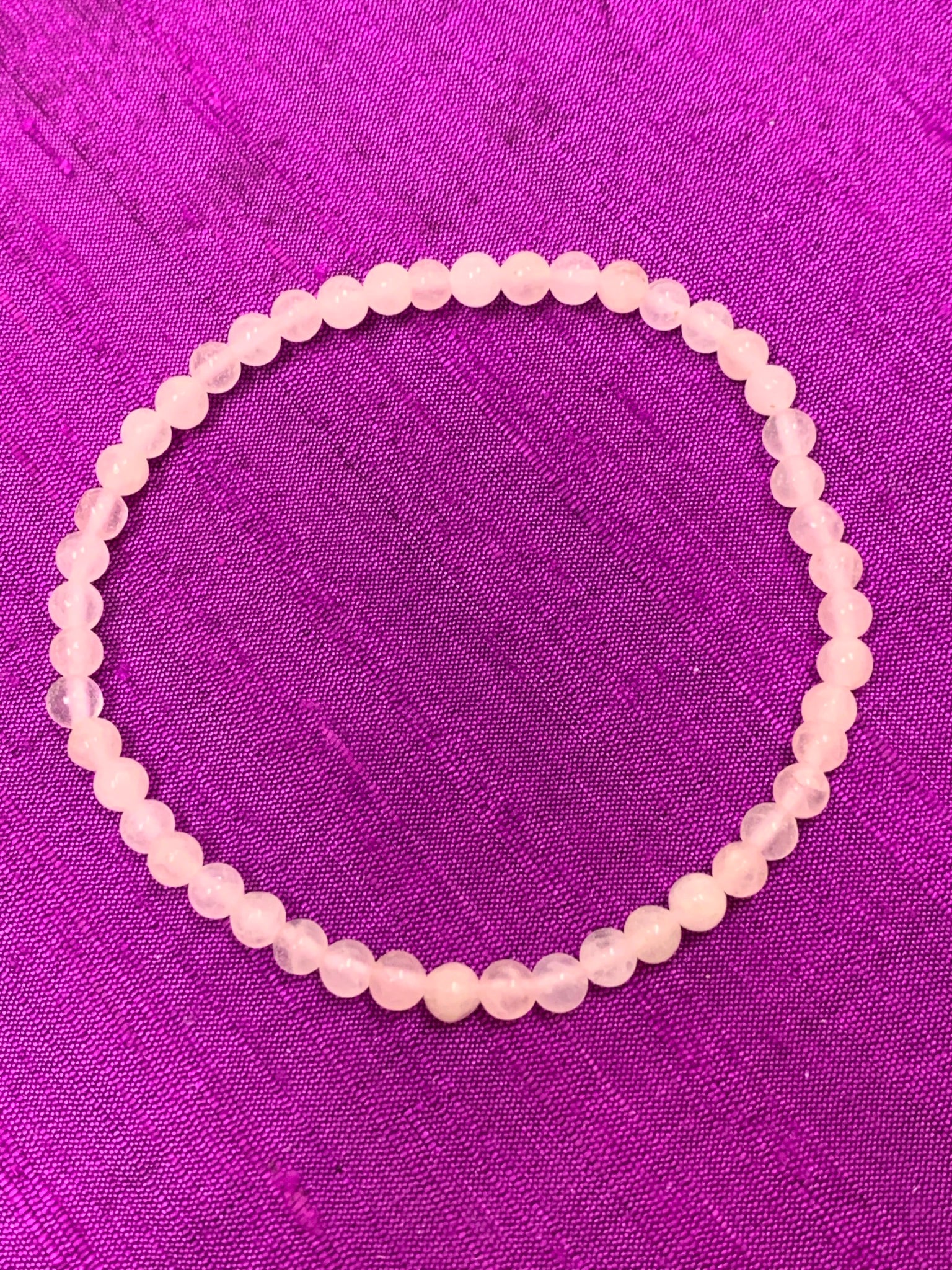 Close-up view. Petite rose quartz power bracelet. Beads are 4mm. Tiny and mighty, these bracelets put the soft power of rose quartz right around your wrist. Buy one or buy several and wear and share them with friends or family - we have a variety of gemstone choices.