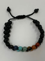 Load image into Gallery viewer, Close-up view. Adjustable lava power bracelet with double rows, one on top of the other, of both lava and chakra beads which are tightly strung together with a strong, thin black cord. The bracelet is adjustable. Lava is very grounding, calming and protective. Beads are 8mm. This is one powerful bracelet!
