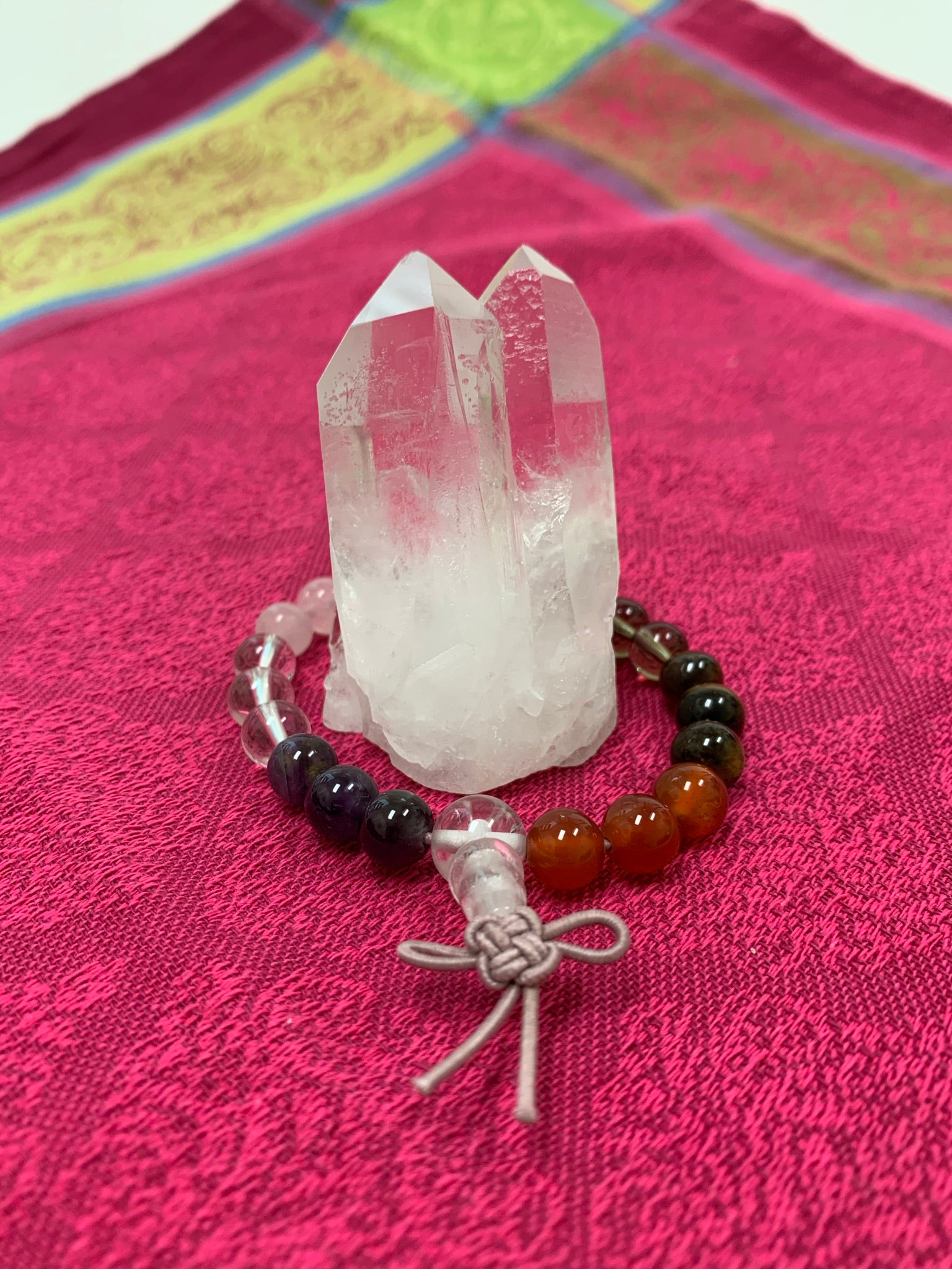 Mixed gemstone power bracelet with 7 different gemstones: amethyst, clear quartz, rose quartz, smoky quartz, tiger eye, carnelian, and aventurine. The bracelet is accented by a Chinese tassel knot.