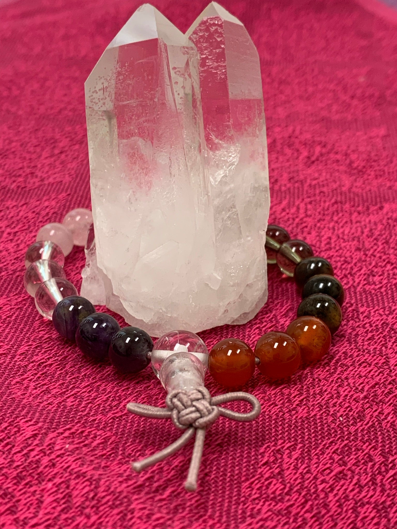 Second close-up view. Mixed gemstone power bracelet with 7 different gemstones: amethyst, clear quartz, rose quartz, smoky quartz, tiger eye, carnelian, and aventurine. The bracelet is accented by a Chinese tassel knot.