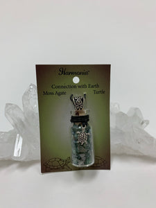 Small corked gemstone chip bottle necklace with moss agate gemstone chips inside, accented with a silver-colored turtle and fancy jewelry bail on the outside. Comes with a thin suede cord to wear as necklace.
