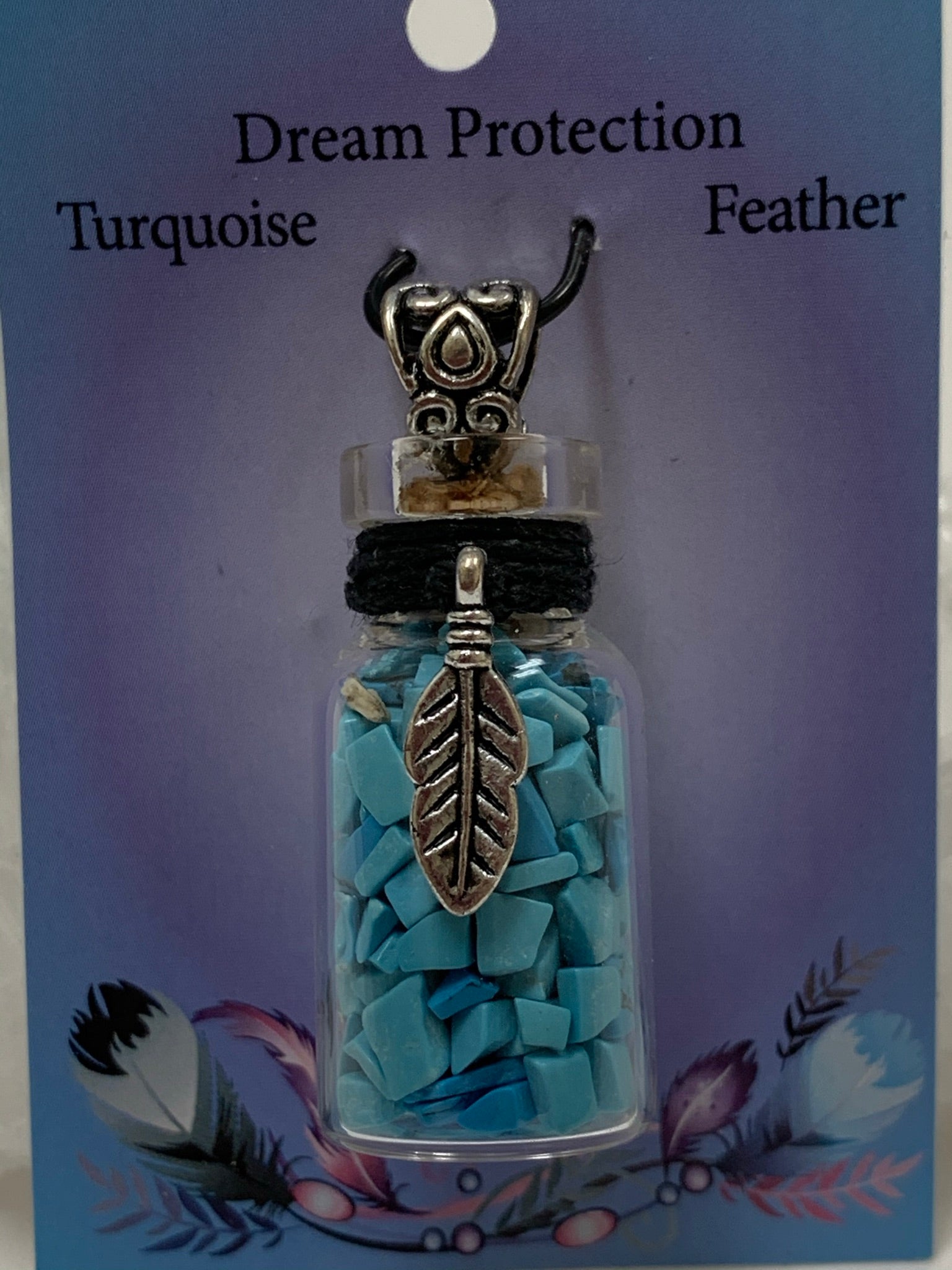 Close-up view of the gemstone (corked) chip bottle necklace with little turquoise chips inside, accented by a silver-colored feather and fancy jewelry bail on the outside. Silver is not sterling. Thin suede cord is included to be used as a necklace.