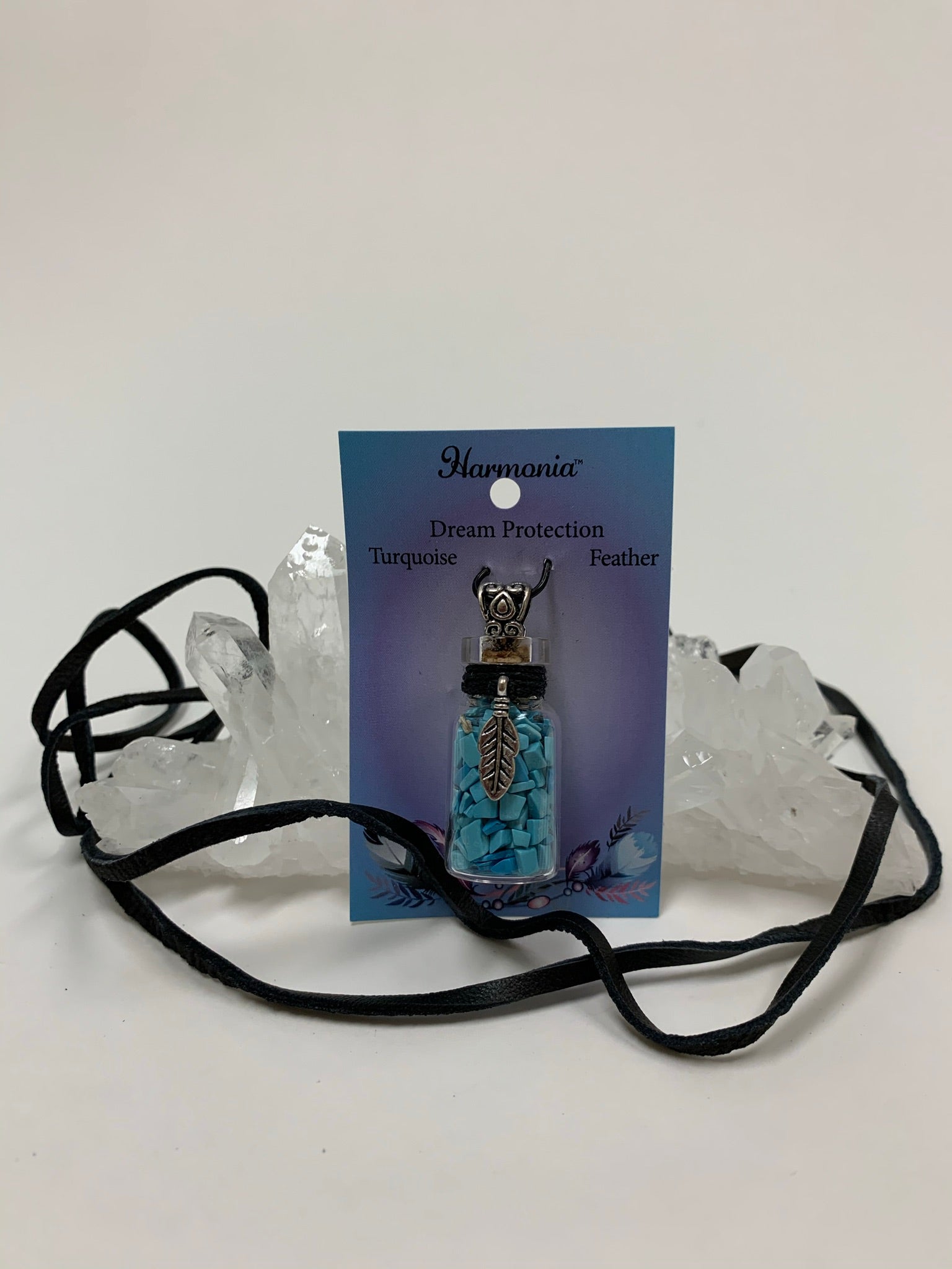 View with suede cord displayed. Gemstone (corked) chip bottle necklace with little turquoise chips inside, accented by a silver-colored feather and fancy jewelry bail on the outside. Silver is not sterling. Thin suede cord is included to be used as a necklace.