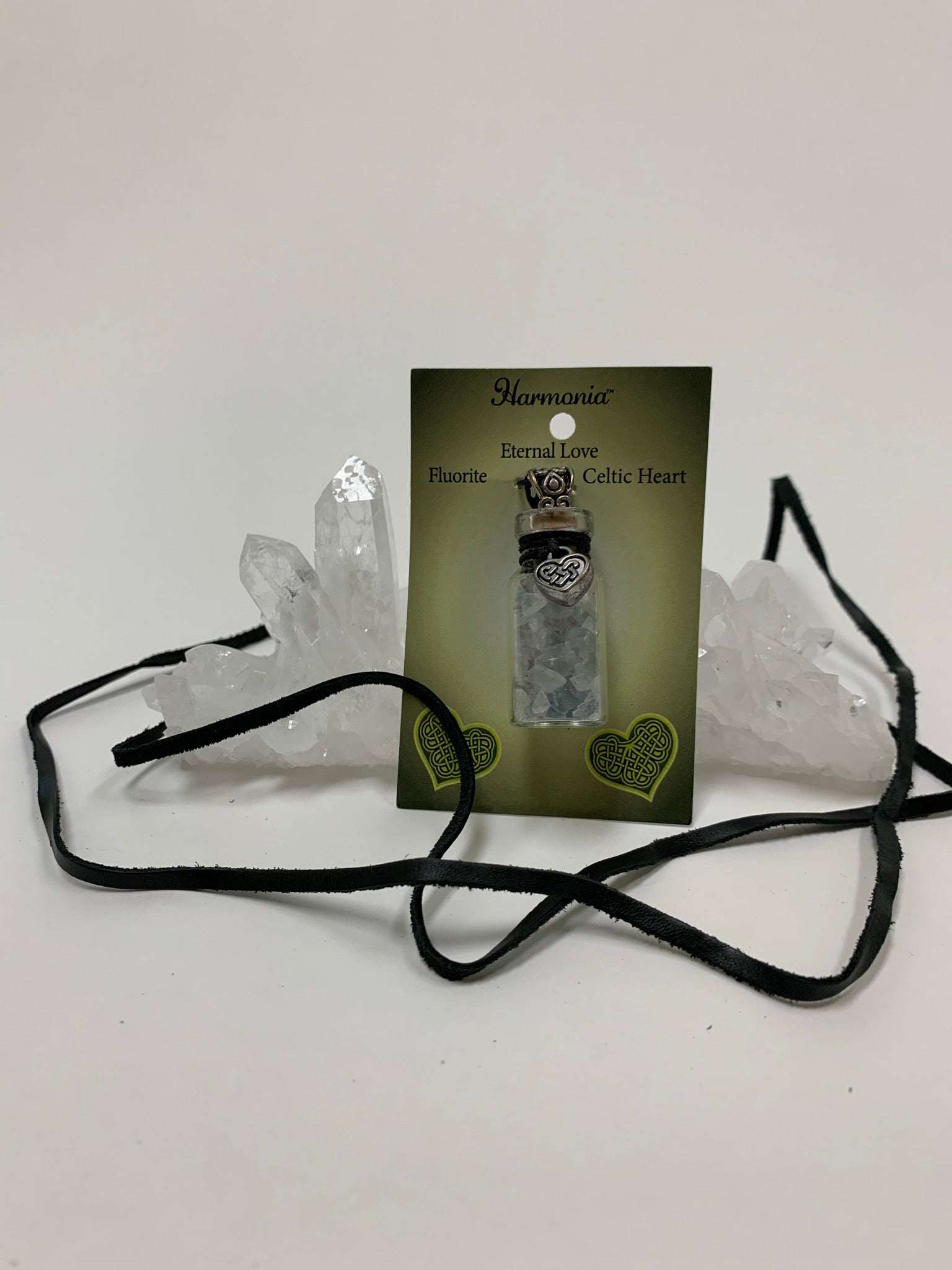 View displaying black suede cord included with the Gemstone chip (corked) bottle necklace with little fluorite chips inside and accented on the outside with a silver-colored Celtic heart and a fancy jewelry bail. It comes with a thin black suede cord so the bottle can be worn as a necklace.