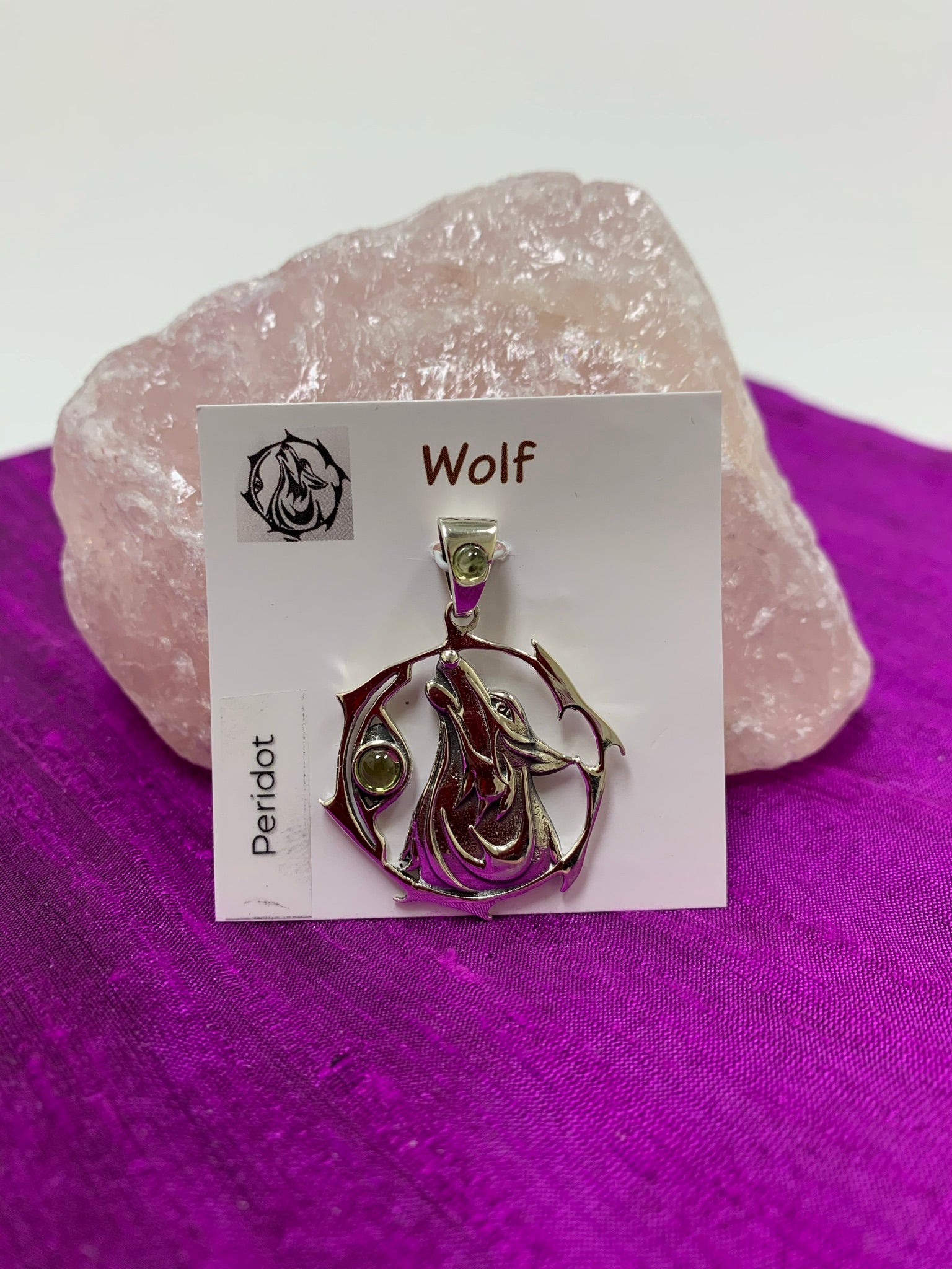 Sterling Silver wolf spirit animal pendant. Howling wolf (head and part of body) inside a fancy, stylized circle. Two peridot gemstones (cabs), one on the actual pendant and one on the bail. Wear your spirit animal on your chest and carry it with you wherever you go! (Pendant only, no necklace chain). 