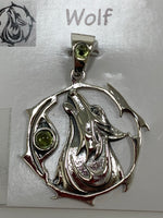 Load image into Gallery viewer, Close-up view of the sterling silver wolf spirit animal pendant. Howling wolf (head and part of body) inside a fancy, stylized circle. Two peridot gemstones (cabs), one on the actual pendant and one on the bail. Wear your spirit animal on your chest and carry it with you wherever you go! (Pendant only, no necklace chain).
