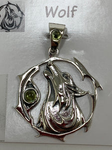 Close-up view of the sterling silver wolf spirit animal pendant. Howling wolf (head and part of body) inside a fancy, stylized circle. Two peridot gemstones (cabs), one on the actual pendant and one on the bail. Wear your spirit animal on your chest and carry it with you wherever you go! (Pendant only, no necklace chain).