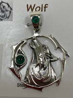 Load image into Gallery viewer, Close-up view of the sterling silver wolf spirit animal pendant. The sterling silver wolf is howling and consists of the head, neck and part of the body. It is inside of a stylized sterling circle and has two green onyx gemstones (cabs), one on the actual pendant, beside the wolf, and one on the pendant&#39;s bail. Wear this wolf symbol on your chest and carry its energy wherever you go. This is a pendant only - there is not a necklace chain included.
