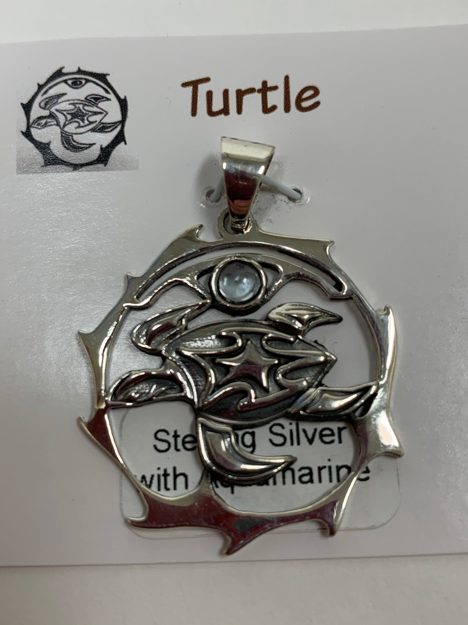 Close-up view. Sterling silver spirit animal, sea turtle, pendant accented with an aquamarine gemstone. Sea turtle is set in an open, sterling silver, circle with the aquamarine above it. Wear your spirit animal so you have it everywhere you go! Pendant only - necklace chain not included.