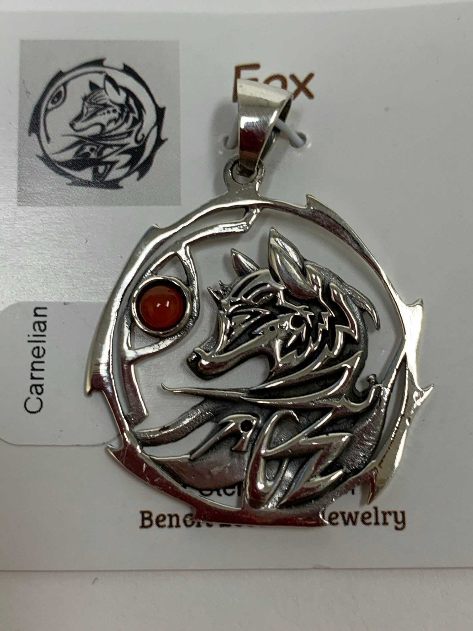 Close-up view. Sterling silver fox animal spirit pendant accented with a carnelian gemstone. The sterling silver fox is set inside an open, stylized sterling silver circle with the carnelian alongside of it. Wear your spirit animal and take its energy everywhere you go! Pendant only - necklace chain not included.