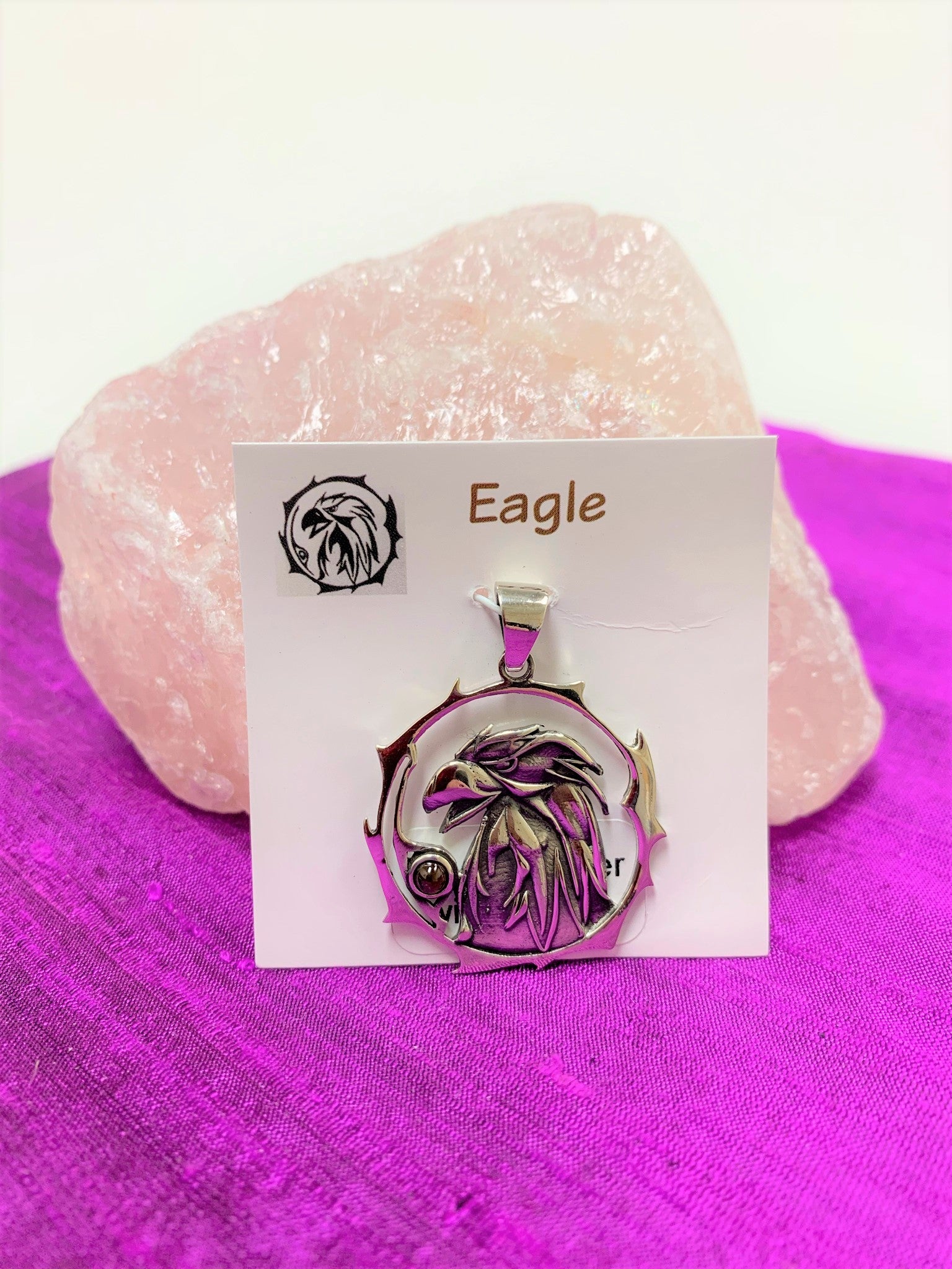 Sterling silver eagle spirit animal pendant, accented with a garnet gemstone. Eagle (head and neck) is set within an open, stylized circle with the gemstone along the side (eagle and circle are sterling). Wear your spirit animal so you can have it wherever you go! Pendant only - necklace chain not included. 