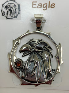 Close-up view. Sterling silver eagle spirit animal pendant, accented with a garnet gemstone. Eagle (head and neck) is set within an open, stylized circle with the gemstone along the side (eagle and circle are sterling). Wear your spirit animal so you can have it wherever you go! Pendant only - necklace chain not included.