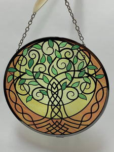 Close-up view. Suncatcher with tree of life design in greens, yellows, gold and black. Beauty and spiritual meaning - sweet combo! Comes with thin chain for hanging and suction cup to hold it.