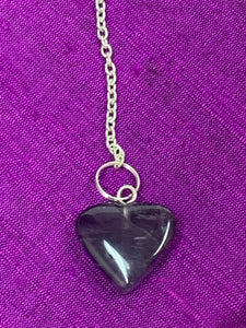 Close-up view of the amethyst heart at the end of the pendulum chain.