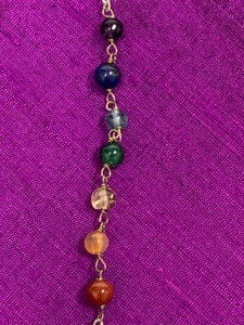 Close-up view of the 7 chakra gemstone beads that run along the silver-colored (not sterling) chain of the pendulum.