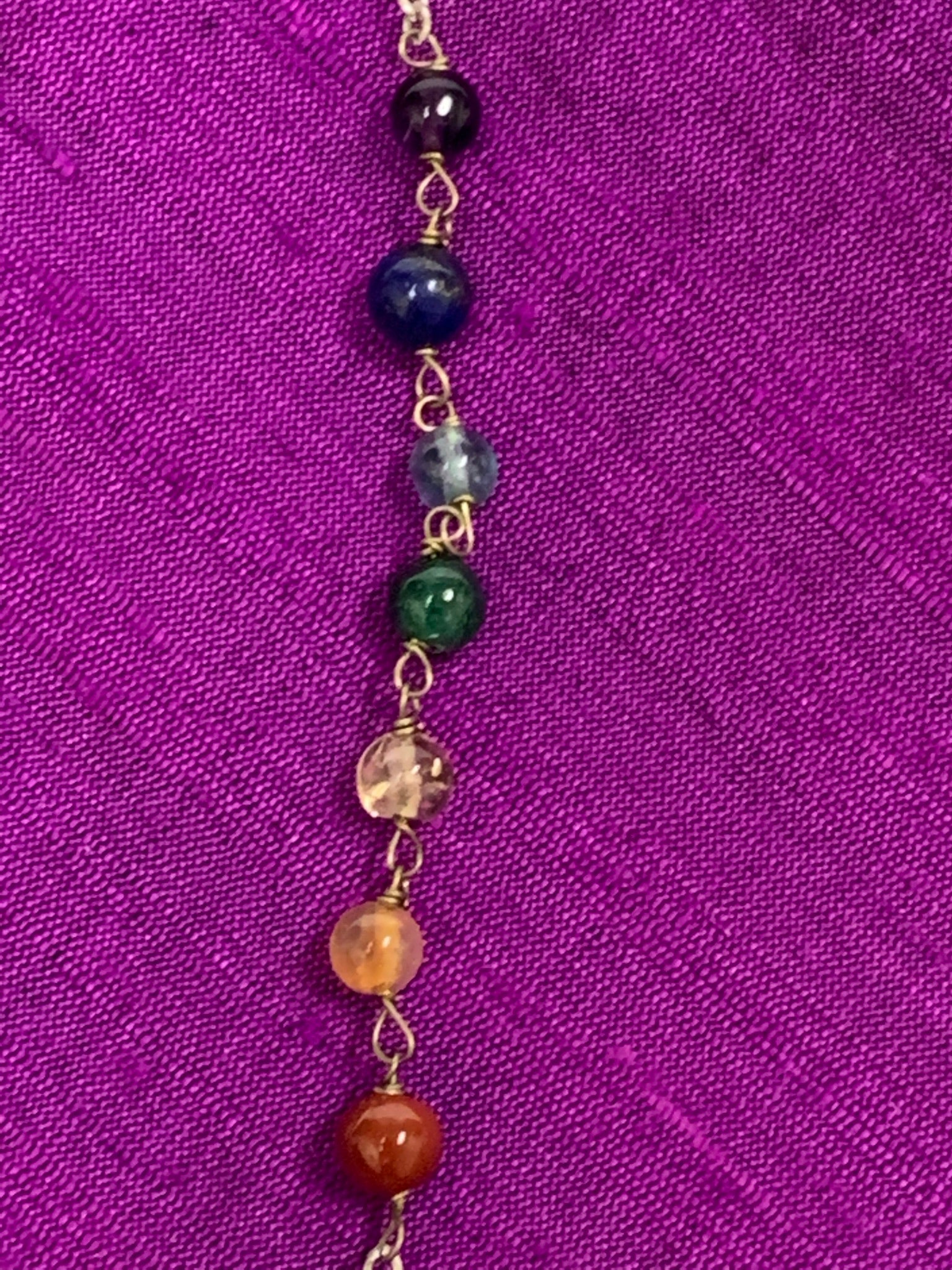 Close-up view of the 7 chakra gemstone beads on the pendulum's chain.