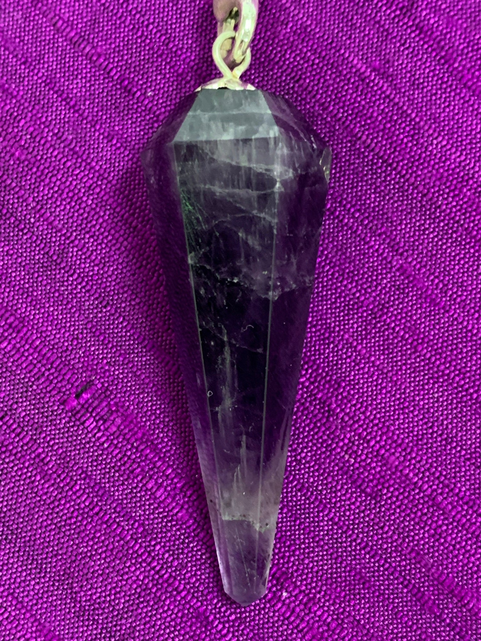 Close-up view of the amethyst stone at the end of the pendulum chain. 