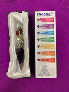 Amethyst pendulum with silver-colored chain, accented by 7 chakra beads is shown displayed in its white satiny lined box, displaying the names of the 7 major chakras, the color of each and the name of each chakra bead on the pendulum chain. 