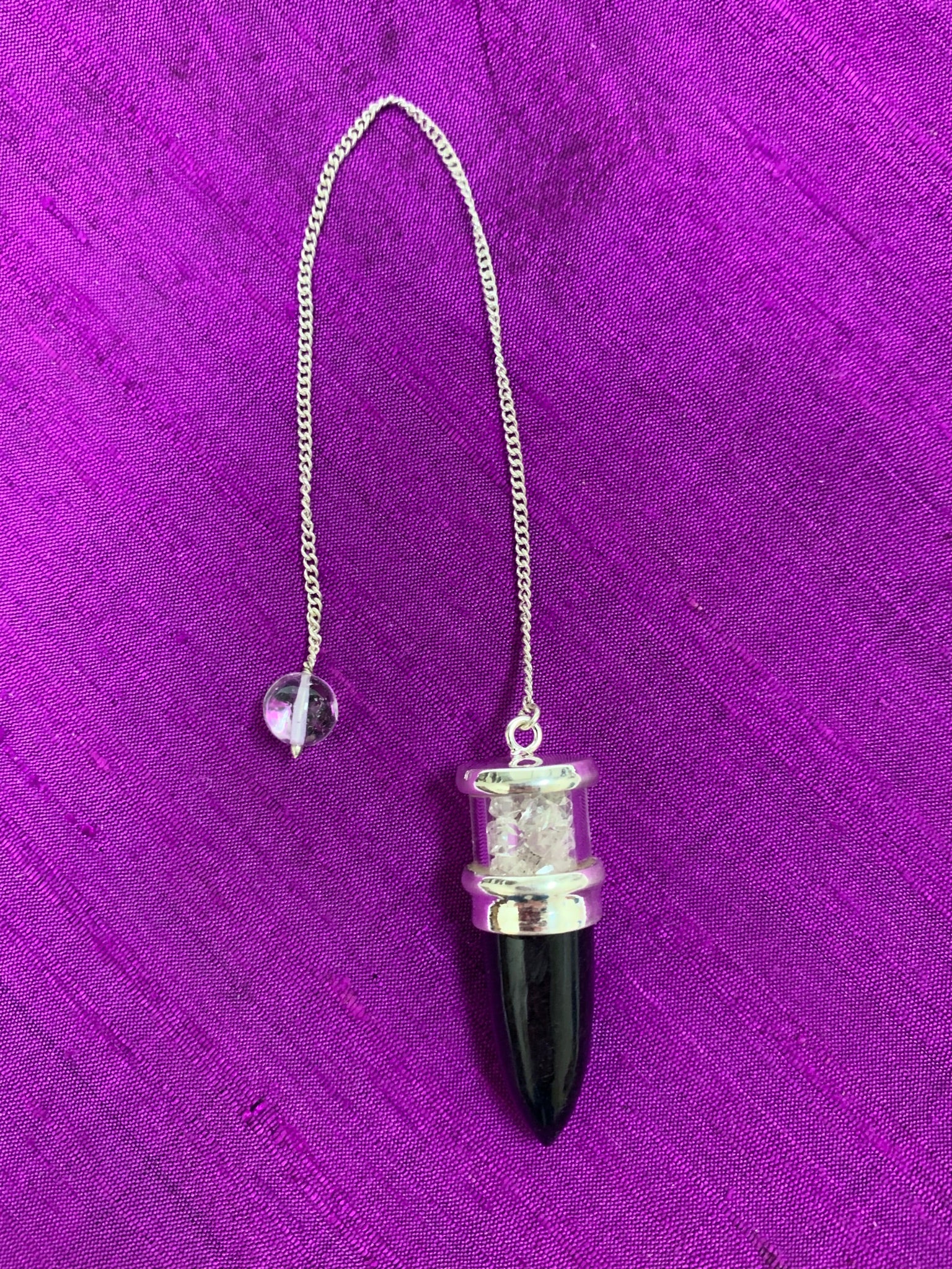 Elegant pendulum with black tourmaline gemstone set in sterling silver with Herkimer diamond chips above it, encased in glass and a clear quartz bead at the opposite end of the silver chain. Pendulums are used as divination tools for receiving information from your guides, angels and higher Self. Cost is $30.