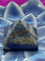 Load image into Gallery viewer, Close-up view. Powerful lapis pyramid is perfect for your altar, meditation space or anywhere in your home or office. Lapis enhances intuition and psychic abilities, brings peace and serenity, reveals inner truths, aids in self-expression, activates the third eye and and brings balance to the throat chakra. Pyramids are used to amplify and transform energy. Today &quot;their likeness is used to charge crystals, herbs, pendulums, water, essential oils and other items. Approximately 1&quot;x1&quot;.
