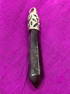 Close-up view. Long amethyst crystal point is set in a fancy silver bail (not sterling silver) for this powerful pendant. Amethyst, one of the most spiritual gemstones, heals, cleanses & calms, allowing you to reach meditative & higher consciousness levels more easily. It also helps to dispel negative emotional states. Perfect for wearing to take advantage of its benefits all day long. Approximately 2½".