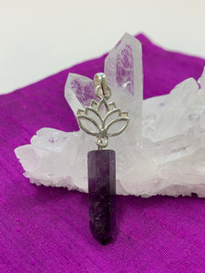 Amethyst crystal point dangles from an open sterling silver lotus. Amethyst, one of the most spiritual gemstones, heals, cleanses & calms, allowing you to reach meditative & higher consciousness levels more easily. It also helps to dispel negative emotional states. The lotus represents purity, strength and enlightenment. Approximately 2¼".