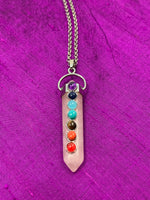 Load image into Gallery viewer, Close-up view. Double terminated rose quartz crystal is set in a silver-plated bail (not sterling silver) for this powerful pendant and comes with a necklace chain. Rose quartz is the &quot;stone of unconditional love &amp; infinite peace.&quot; It opens the heart and soothes emotional distress. Small chakra stones sit on the pendant, one for each of the 7 major chakras. Perfect for wearing to take advantage of its benefits all day long. Approximately 2&quot;.
