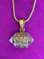 Load image into Gallery viewer, Close-up view. Clear quartz seed necklace. Hand-cast, hypoallergenic brass Seed of Life design wraps around a double-terminated (horizontally set) clear quartz crystal and strung (with a brass bail) on an adjustable 16-20&quot; necklace chain. The Seed of Life is a universal symbol for creation (and much more). Although very beautiful, the handcrafting means you may find differences between necklaces and slight variations or imperfections.
