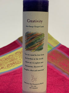 Close-up view of the Reiki-charged pillar candle for "creativity." It is handcrafted and scented using essential oils. An affirmation/prayer is printed on the label, as well as a listing of the essential oils used (iris, rose & cinnamon). It is approximately 7"x2½." Perfect for Meditation, prayer, visualization or quiet time. This dark blue candle and its label are both visually appealing.