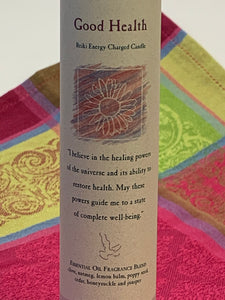 Close-up view of the Reiki-charged pillar candle for "Good Health." It is handcrafted and scented using essential oils. An affirmation/prayer is printed on the label, as well as a listing of the essential oils used (clove, nutmeg, lemon balm, poppy seed, cedar, honeysuckle, juniper). It is approximately 7"x2½." Perfect for meditation, prayer, visualization or quiet time. This dark blue candle and its label are both visually appealing.