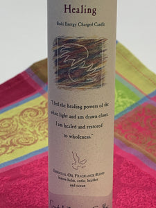 Close-up view of the Reiki-charged pillar candle for "Healing." It is handcrafted and scented using essential oils. An affirmation/prayer is printed on the label, a well as a listing of the essential oils used (lemon balm, cedar, heather, ocean). It is approximately 7"x2½". Perfect for meditation, prayer, visualization or quiet time. This deep purple candle and its label are both visually appealing.