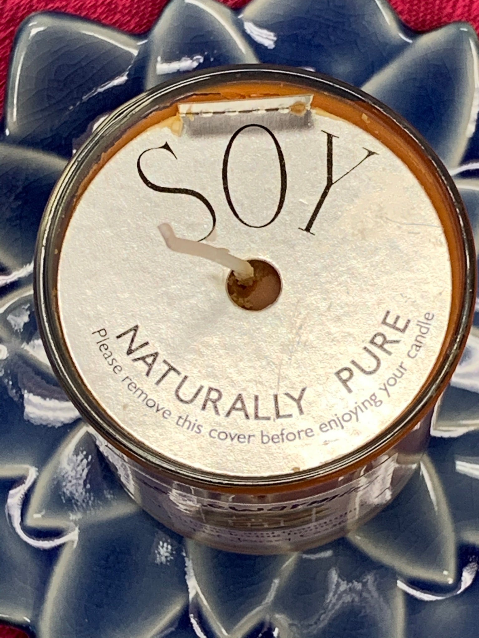 Close-up view from above the candle showing its silver-colored, paperboard, protective covering.