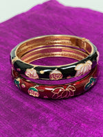 Load image into Gallery viewer, Close up, both bracelets. Set of 2 beautiful bangle bracelets (red and black) with intricate metal work and enamel finish. Apparently when enamel is heated up to very high temperatures, it becomes &quot;vibrant in color with a wonderful metallic finish.&quot; The design includes lovely lotus flowers. Lotus symbolizes purity, strength and enlightenment and reminds us that we all must move through the muck to reach the light ♥. See the other set in my store (purple and green).
