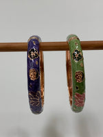 Load image into Gallery viewer, Set of 2 beautiful bangle bracelets (purple &amp; green) with intricate metal work and enamel finish. Apparently when enamel is heated up to very high temperatures, it becomes &quot;vibrant in color with a wonderful metallic finish.&quot; The design includes lovely lotus flowers. Lotus symbolizes purity, strength and enlightenment and reminds us that we all must move through the muck to reach the light ♥. See the other set in my store (black &amp; red).
