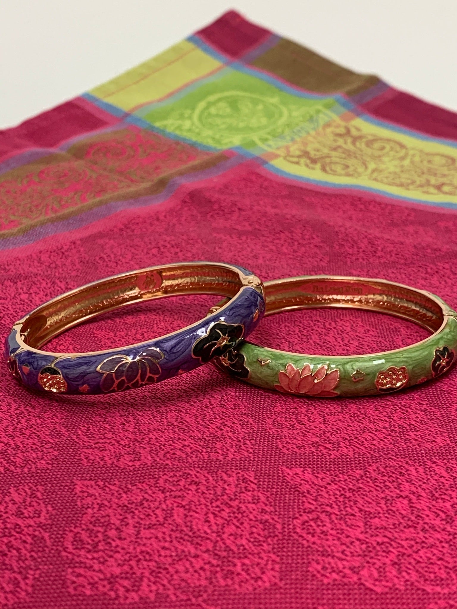 Close-up, both bracelets. Set of 2 beautiful bangle bracelets (purple & green) with intricate metal work and enamel finish. Apparently when enamel is heated up to very high temperatures, it becomes "vibrant in color with a wonderful metallic finish." The design includes lovely lotus flowers. Lotus symbolizes purity, strength and enlightenment and reminds us that we all must move through the muck to reach the light ♥. See the other set in my store (black & red).