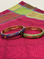 Load image into Gallery viewer, Close-up, both bracelets. Set of 2 beautiful bangle bracelets (purple &amp; green) with intricate metal work and enamel finish. Apparently when enamel is heated up to very high temperatures, it becomes &quot;vibrant in color with a wonderful metallic finish.&quot; The design includes lovely lotus flowers. Lotus symbolizes purity, strength and enlightenment and reminds us that we all must move through the muck to reach the light ♥. See the other set in my store (black &amp; red).
