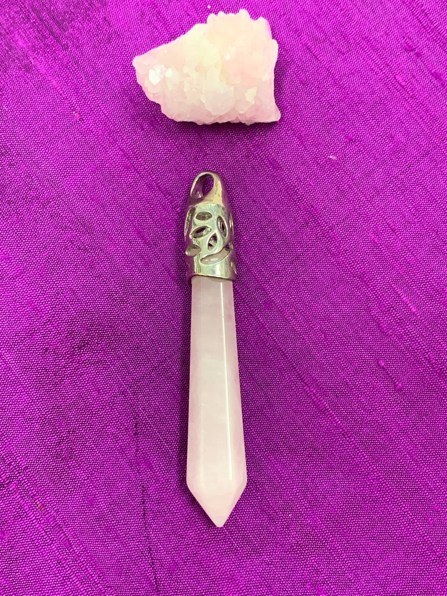 A Second view of the long rose quartz crystal point set in a fancy silver-plated bail (not sterling silver) for this powerful pendant. Rose quartz is the "stone of unconditional love & infinite peace." It opens the heart and soothes emotional distress. Perfect for wearing over your heart to take advantage of its benefits all day long. Approximately 2½-2¾".