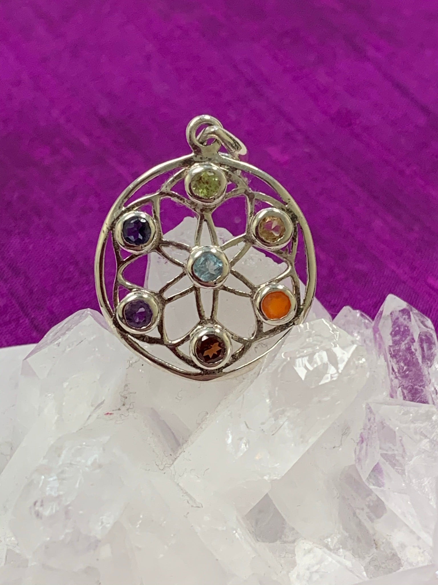 Second close-up view. Beautiful chakra wheel pendant with seven small faceted stones around the wheel, each representing one of the 7 major chakras. Stones are set in sterling silver wheel. Chakras are energy centers in our bodies that process energy - coming into and flowing out of the body. The pendant is approximately 1¼".