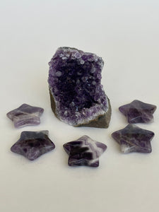 View of several amethyst stars. Love this little chevron amethyst star! The white quartz tips one of the points of the star. It can be used for meditation, healing, for your altar or as décor for any room in your home or office. Easy to slip right into your pocket so you have the energy of amethyst everywhere you go. Approximately 1¼". Cost is $6 for one star. 