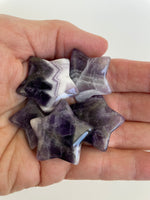 Load image into Gallery viewer, View of several amethyst stars. Love the way the white quartz in this chevron amethyst star tips the point of the star! It can be used for meditation, healing, for your altar or as décor for any room in your home or office. Easy to slip right into your pocket so you have the energy of amethyst everywhere you go. Approximately 1¼&quot;. Cost is $6 for one star. 
