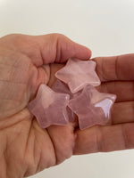 Load image into Gallery viewer, Another view of several rose quartz stars. This sweet little rose quartz crystal star can be used for meditation, healing, as an altar piece or as décor for any room in your home or office. Makes a wonderful gift too! Easy to slip right into your pocket so you can take the energy of rose quartz wherever you go! Rose quartz is the &quot;stone of unconditional love &amp; infinite peace.&quot; (Judy Hall). Approx. 1¼&quot;. Cost is $6.
