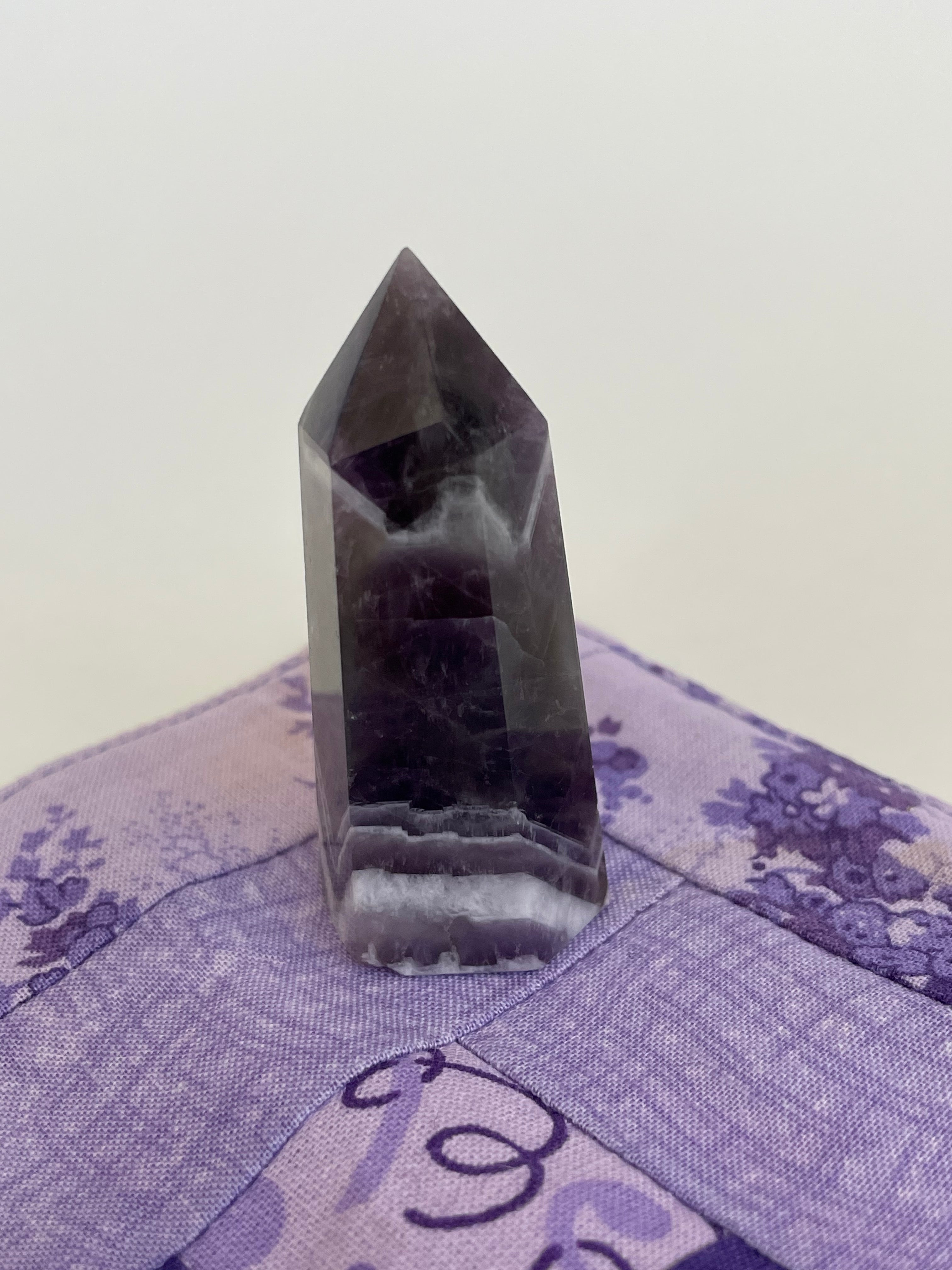 Alternate view. Chevron amethyst tower with the coolest banding for your altar, for healing or as décor for any room in your home or office. Amethyst, one of the most spiritual gemstones, heals, cleanses & calms, allowing you to reach meditative & higher consciousness levels more easily. It also helps to dispel negative emotional states and more. Chevron amethyst is a combination of amethyst and white quartz and when you add the quartz you get additional qualities. 2" long. Cost is $9.