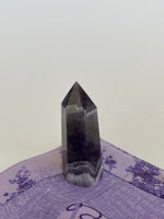 Load image into Gallery viewer, Alternate view. Chevron amethyst tower with the coolest banding for your altar, for healing or as décor for any room in your home or office. Amethyst, one of the most spiritual gemstones, heals, cleanses &amp; calms, allowing you to reach meditative &amp; higher consciousness levels more easily. It also helps to dispel negative emotional states and more. Chevron amethyst is a combination of amethyst and white quartz and when you add the quartz you get additional qualities. 2&quot; long. Cost is $9.
