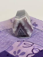 Load image into Gallery viewer, View of cool triangular pattern on bottom of Chevron amethyst tower  for your altar, for healing or as décor for any room in your home or office. Amethyst, one of the most spiritual gemstones, heals, cleanses &amp; calms, allowing you to reach meditative &amp; higher consciousness levels more easily. It also helps to dispel negative emotional states and more. Chevron amethyst is a combination of amethyst and white quartz and when you add the quartz you get additional qualities. 2&quot; long. Cost is $9.
