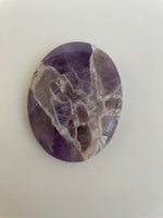 Load image into Gallery viewer, Close up - back. Lovely lavender colored Chevron amethyst palm stone can be used for meditation, healing, for your altar or as a décor item. Amethyst, one of the most spiritual gemstones, heals, cleanses &amp; calms, allowing you to reach meditative &amp; higher consciousness levels more easily. It also helps to dispel negative emotional states and more. Chevron amethyst is a combination of amethyst and white quartz and when you add the quartz you get additional qualities. 2&quot; long. Cost is $12.
