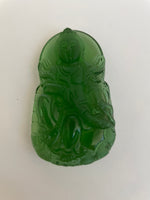 Load image into Gallery viewer, Alternate view. Deep green, glass Buddha can be used as pendant (small hole at top) or as a décor item for your altar or bookshelf. The beautiful detailing makes this a special piece. Buddha is revered around the world and his teachings and actions have shown us the beauty, wonder and power of enlightenment. The term Buddha refers to the Awakened One. . He is approximately 2½&quot; tall. Cost is $10.
