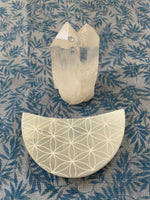 Load image into Gallery viewer, Alternate view. Beautiful selenite crescent moon, etched with the flower of life, can be used for cleansing and charging your crystals and jewelry because it dispels negative and unwanted energies. Selenite also promotes clarity of mind, opens the crown chakra, helps to access angelic energies and guidance from the higher realms. It brings peace and is a great stone to use while meditating or connecting spiritually and more. Approx. 3&quot;. Cost $6.
